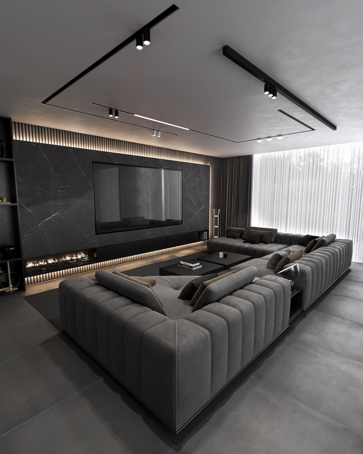 Modern grey living room with a large sectional sofa and integrated fireplace under track lighting.