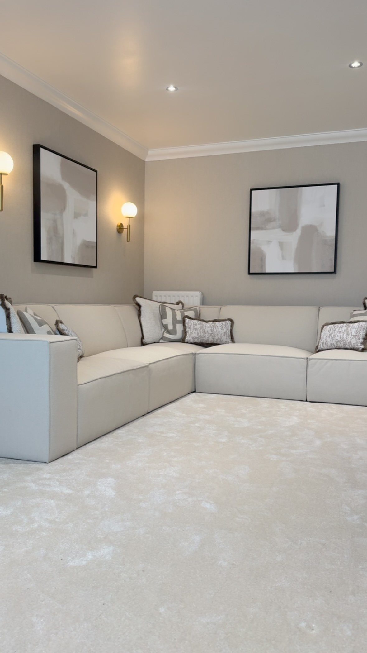 Light grey sectional sofa in a modern living room with grey walls and white molding.