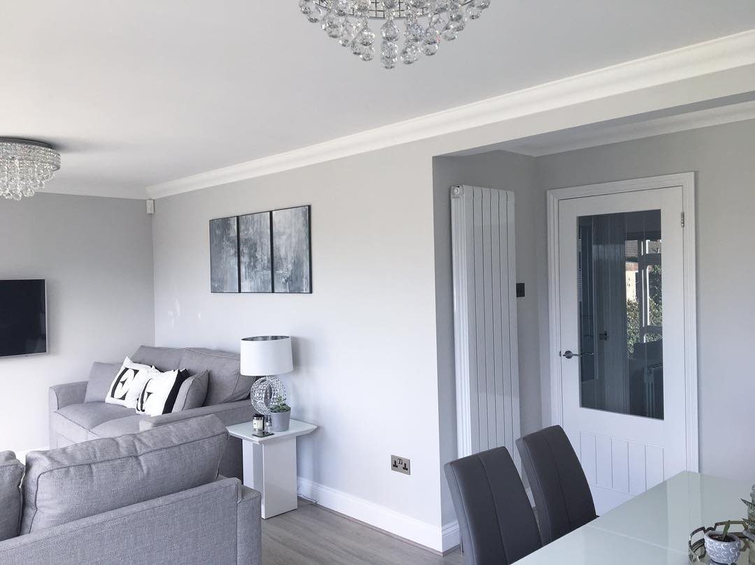 Grey sofas and walls in a modern living room with a crystal chandelier.
