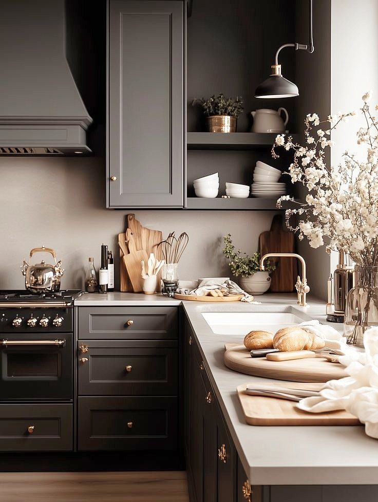 Dark charcoal grey kitchen cabinets and range hood with light countertops and brass accents.