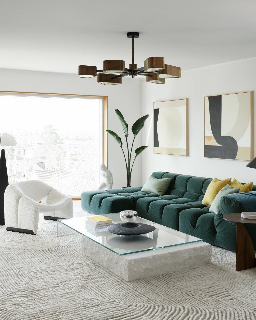 Teal tufted sofa and white sculptural chair in a bright, modern living room.