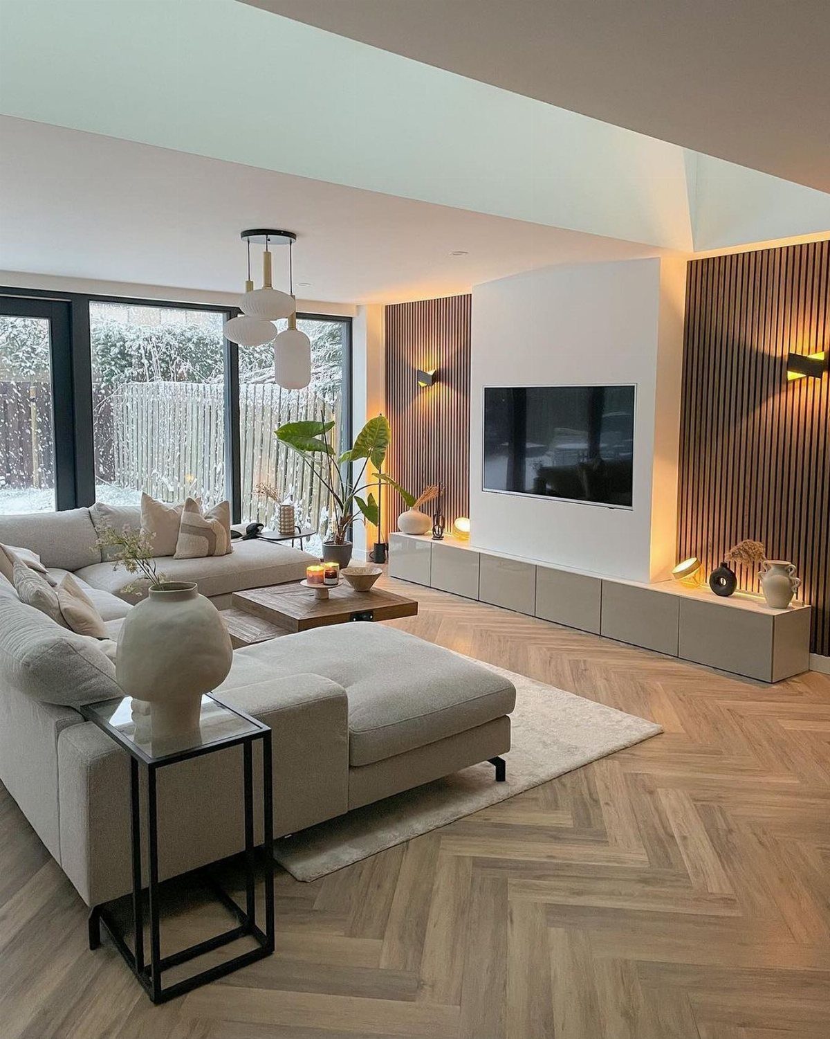 Modern living room with a grey sectional sofa, wooden coffee table, and striped accent wall.