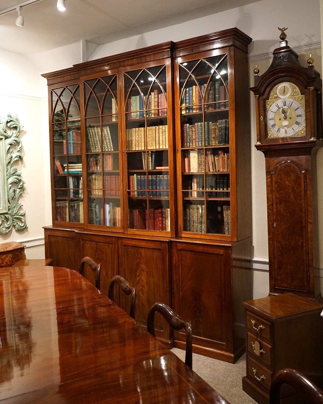 Dark wood Victorian bookcase with glass doors and a tall grandfather clock.