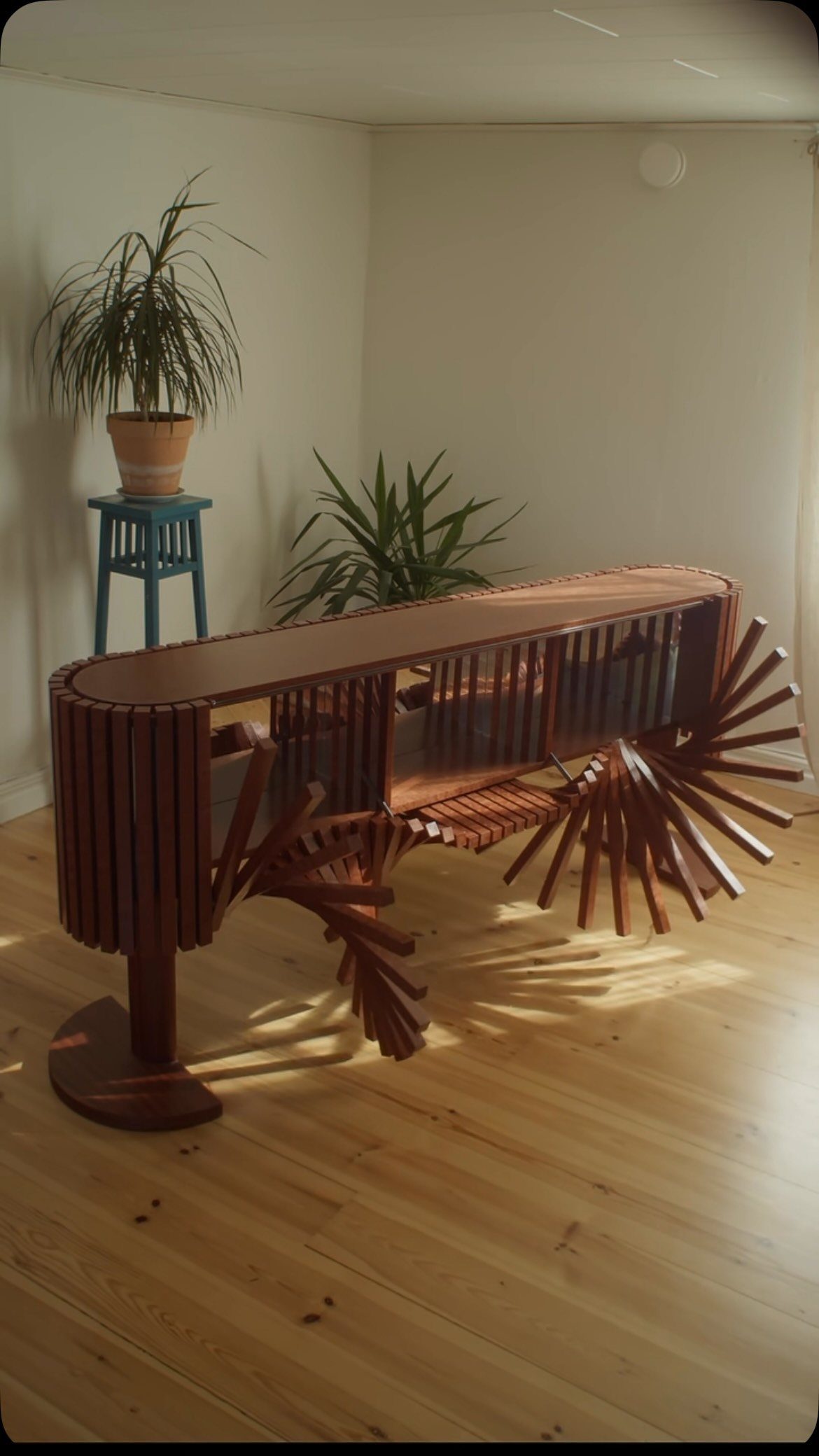 A sculptural wooden slatted sideboard with sunburst legs on a light wood floor.