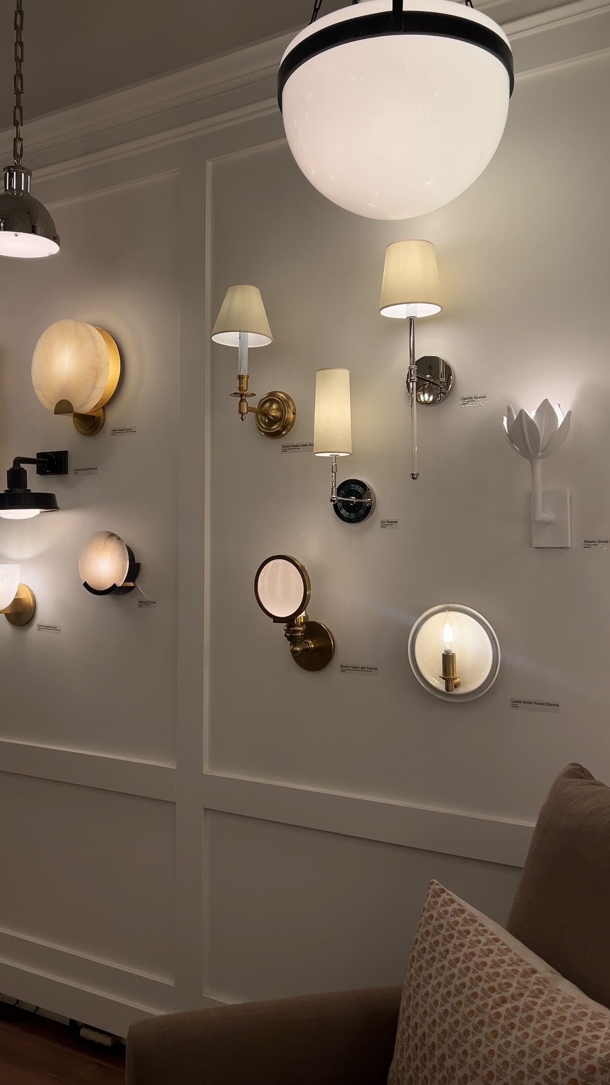 Various modern wall sconces and a globe pendant light displayed on a white paneled wall.