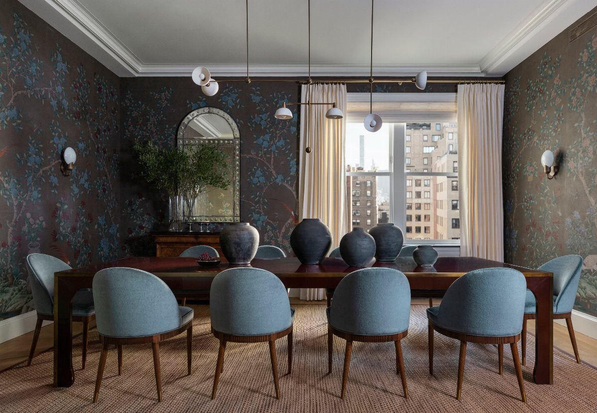 Dark floral patterned wallpaper in a dining room with blue chairs and a wooden table.