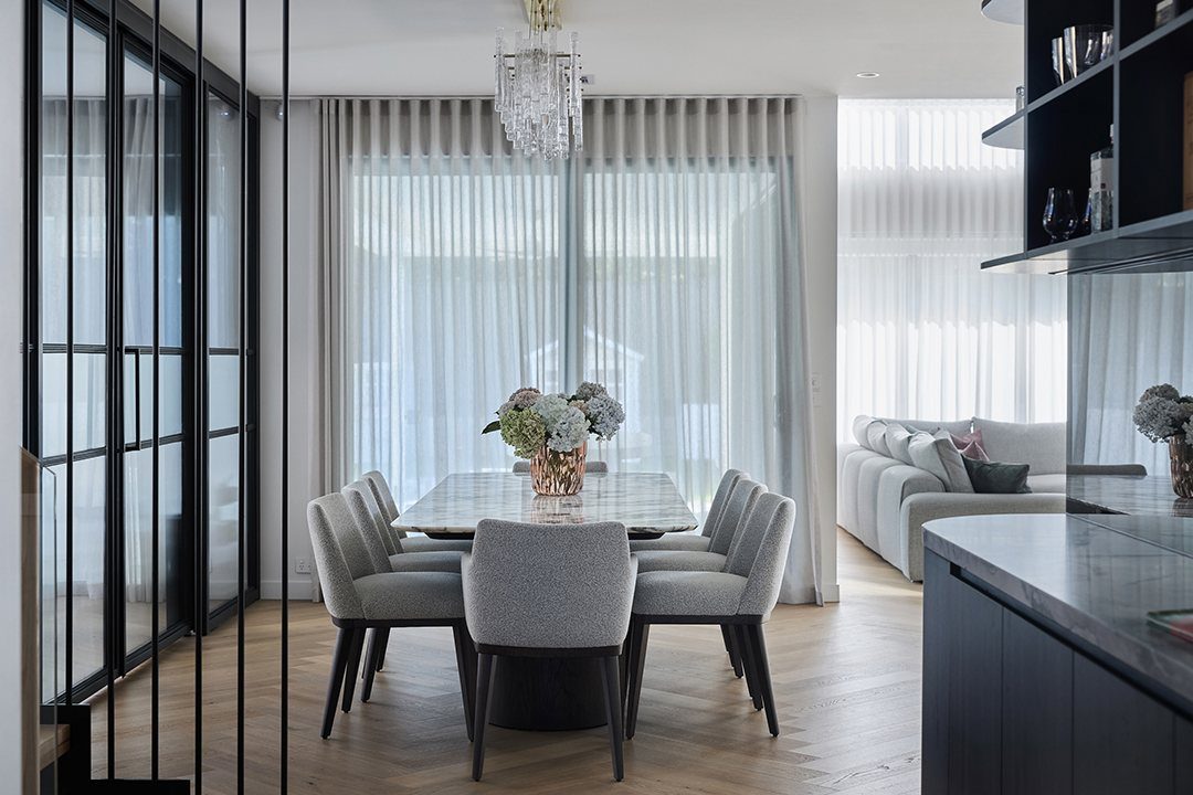 Marble dining table with grey chairs set in a bright, modern dining room.