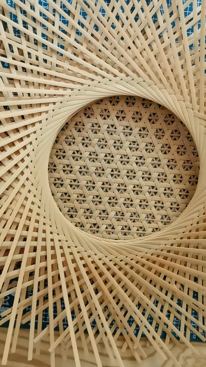 Light wooden strips woven into a circular radiating lattice pattern with a central textured core.