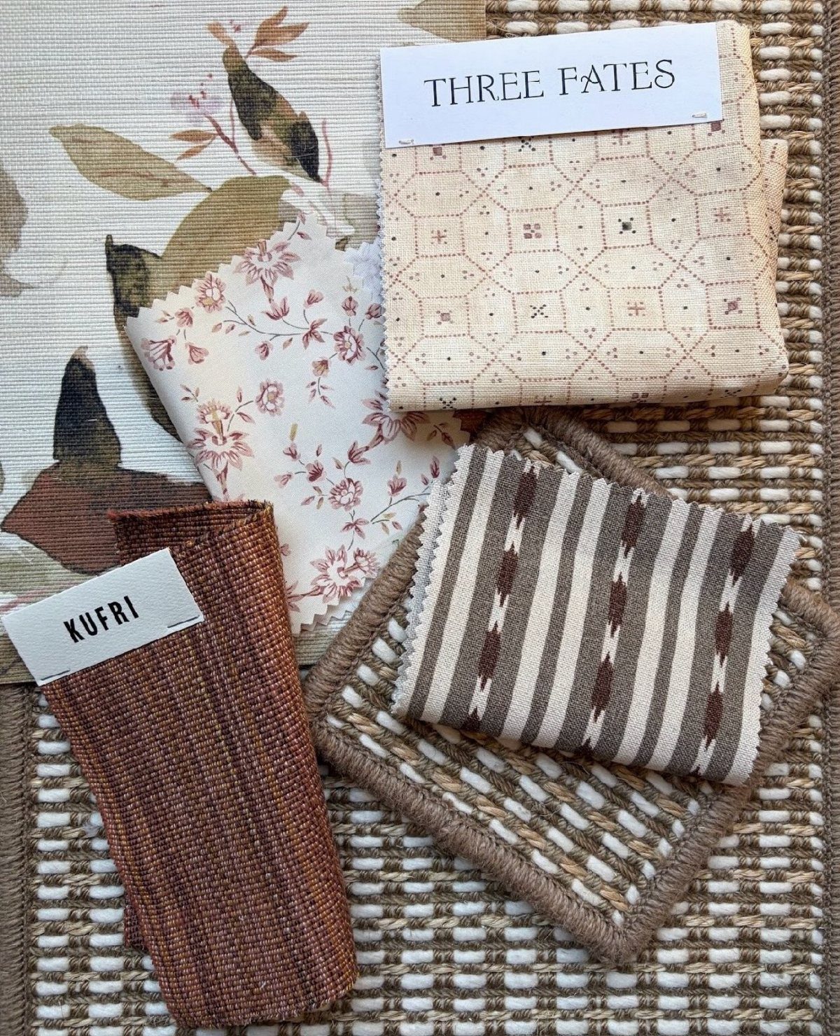 Fabric swatches with floral, striped, and textured patterns laid on a woven rug.