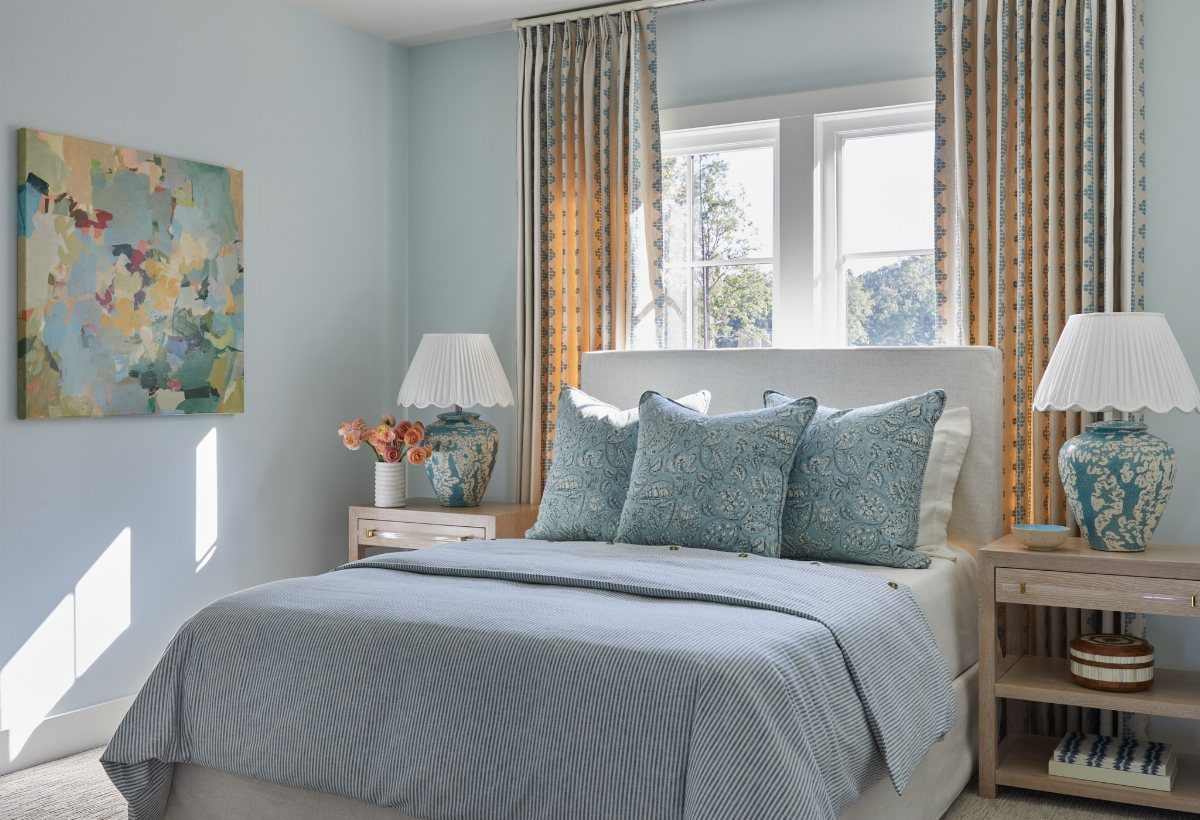 A light blue bedroom with patterned pillows, a textured duvet, and matching blue lamps.