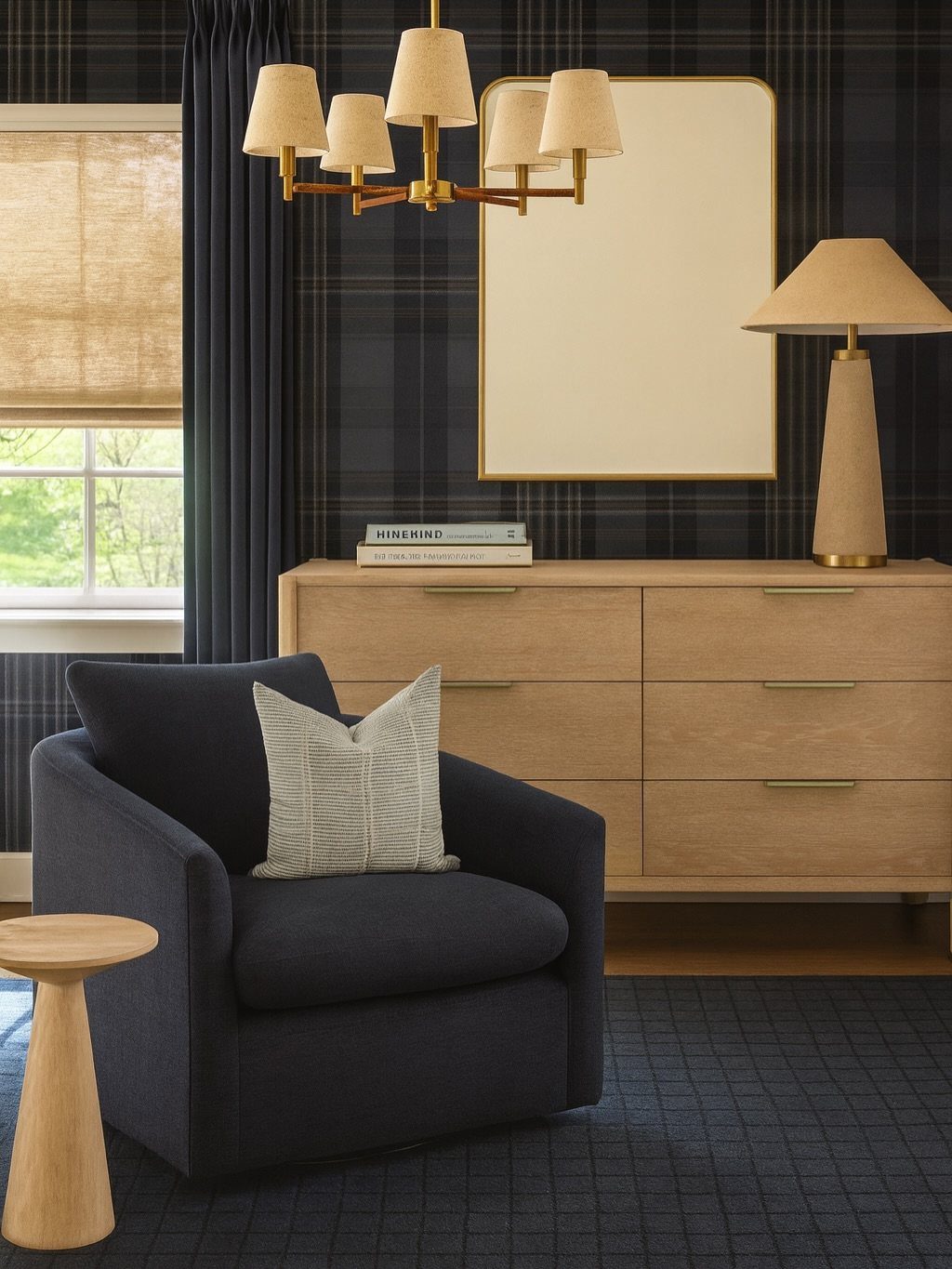 Navy blue armchair and light wood dresser in a room with dark plaid wallpaper.