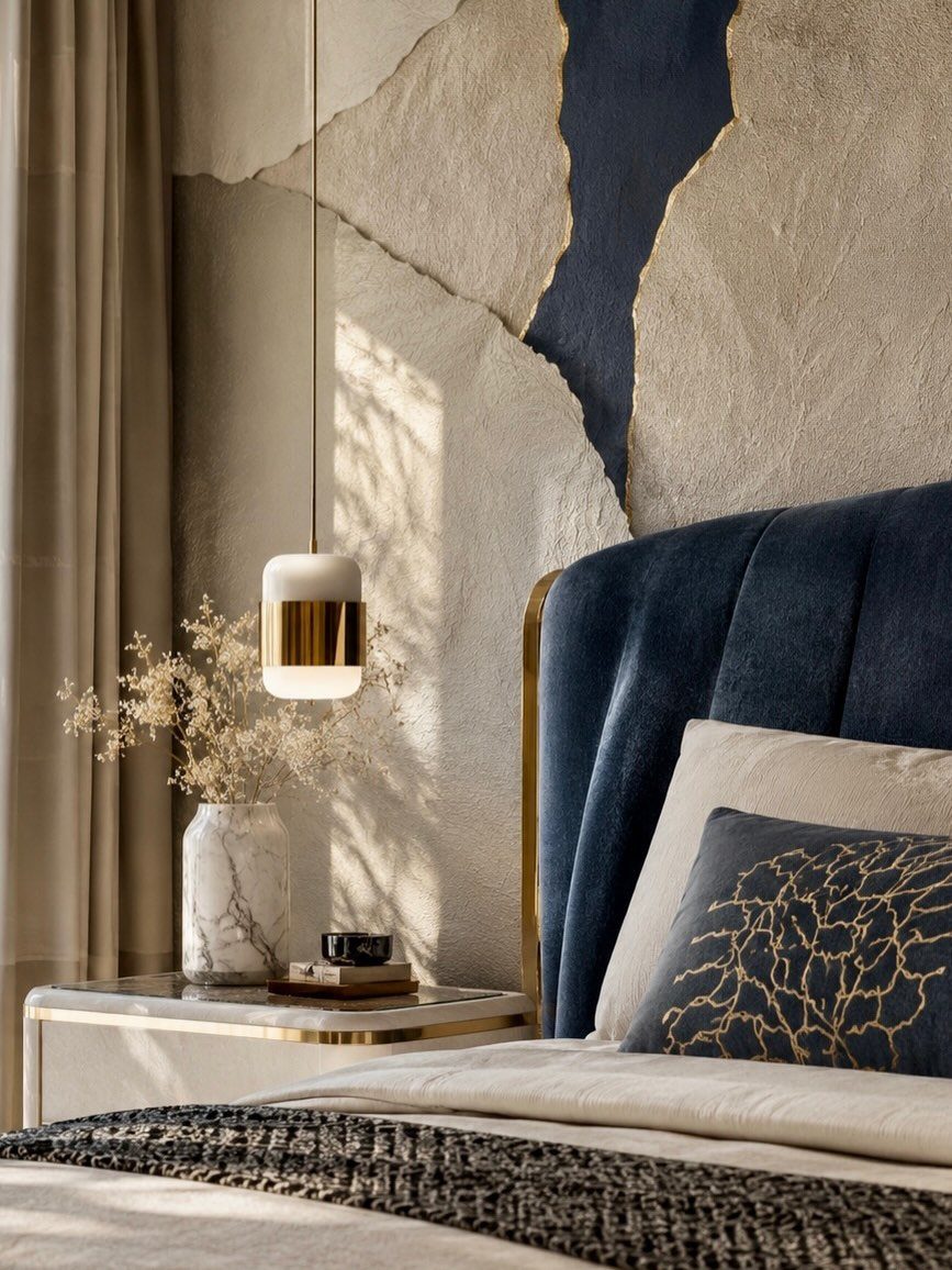 Navy velvet headboard with gold trim next to a bedside lamp and marble vase.