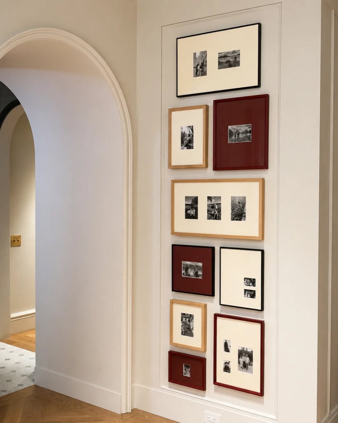 A vertical arrangement of framed black and white photographs on a white wall.
