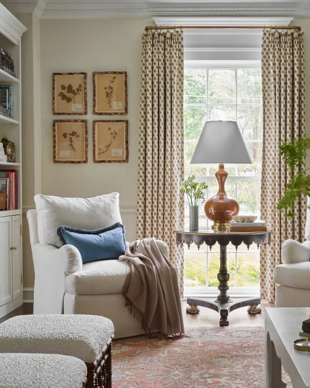 White armchair with blue pillow and tan throw next to a lamp-topped side table.