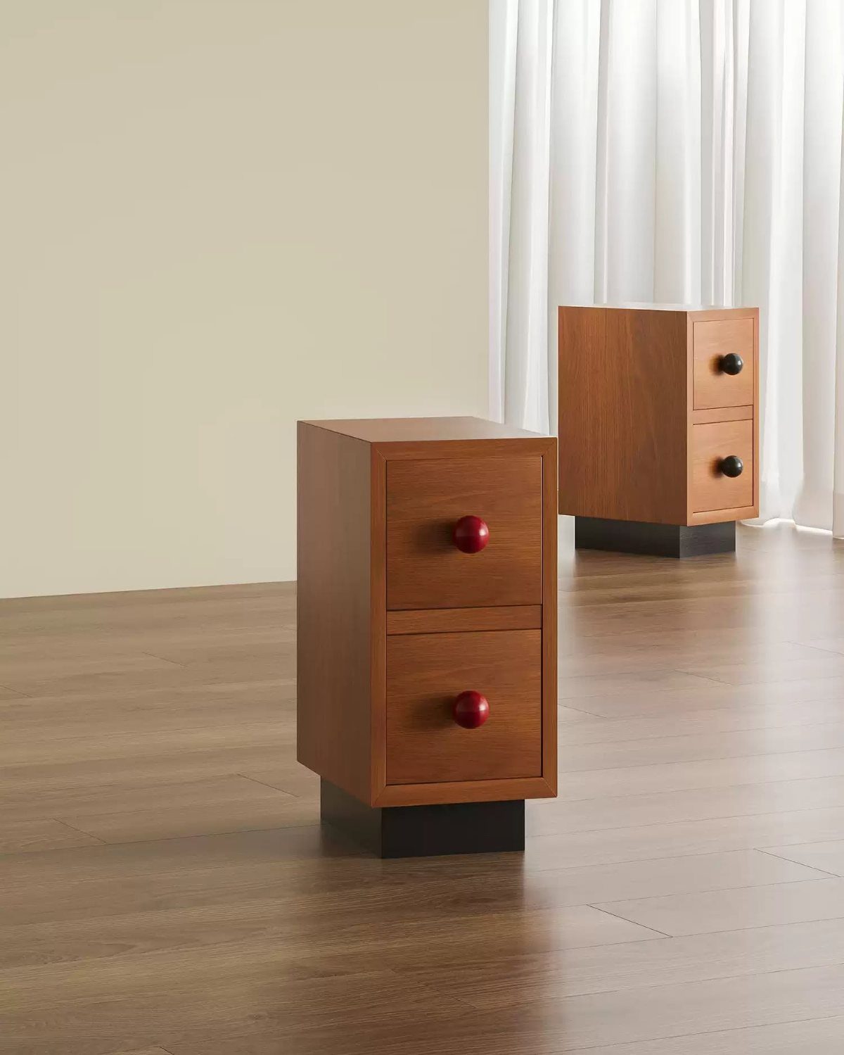 Two compact wooden nightstands with red drawer knobs on a wooden floor.