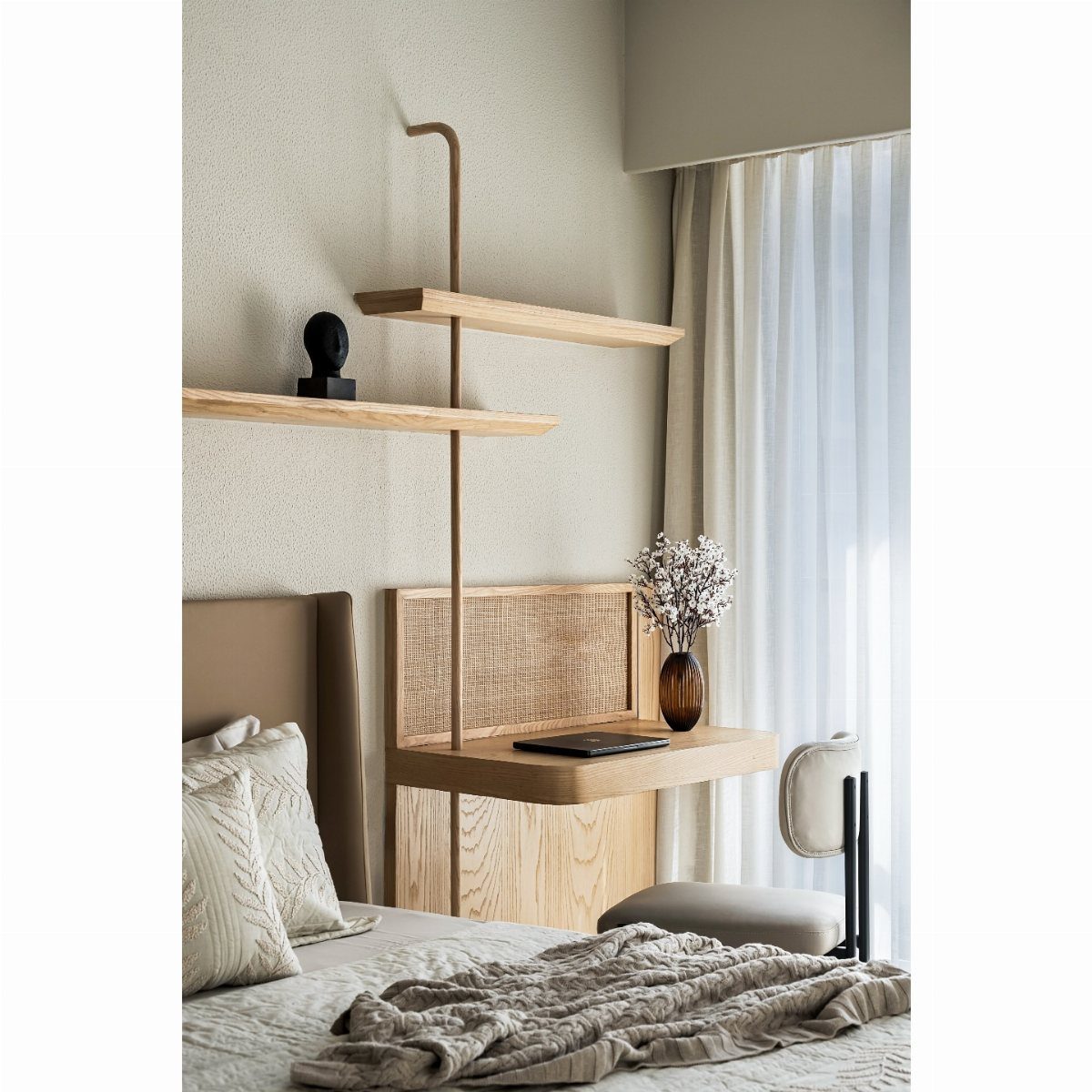 Minimalist wooden floating shelves and a desk surface mounted on a wall above a bed.