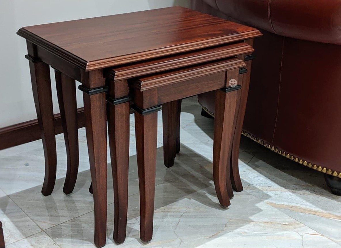 Three dark wood nesting tables with curved legs stacked on a marble floor.