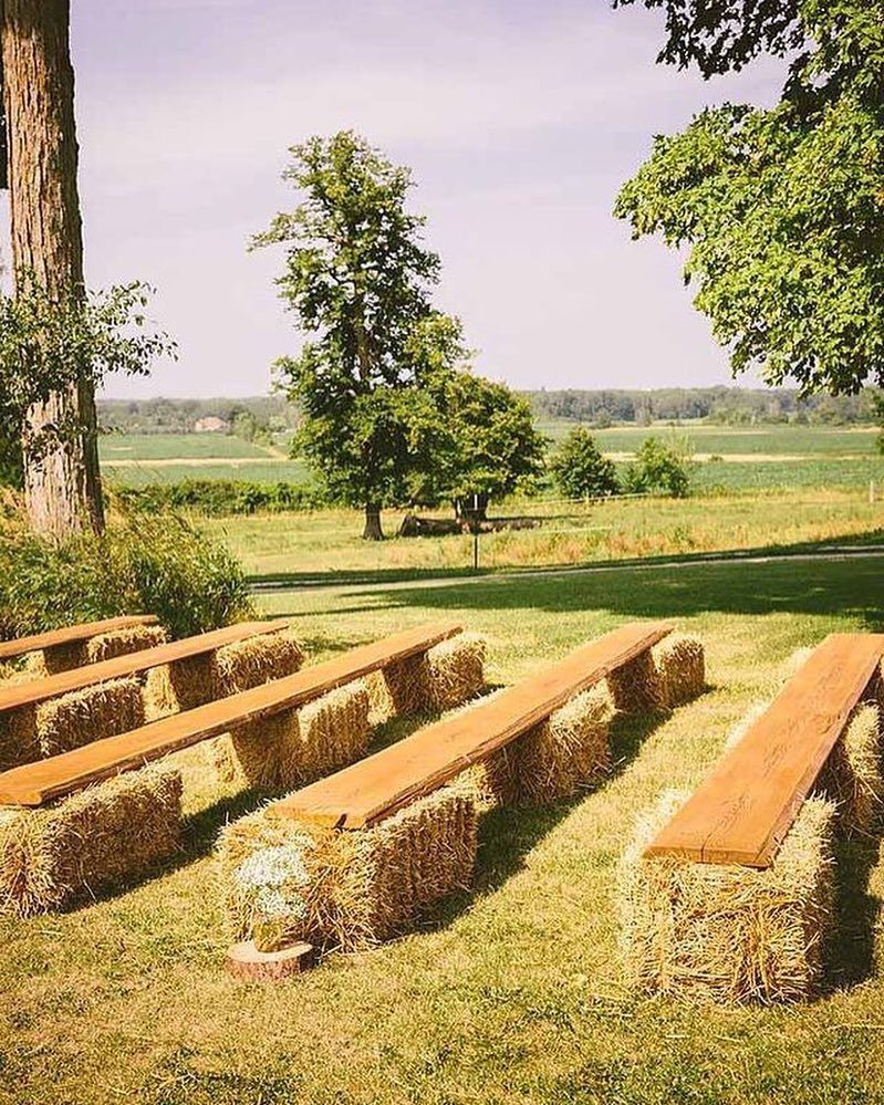 Long wooden planks resting on rows of hay bales serving as rustic outdoor seating.