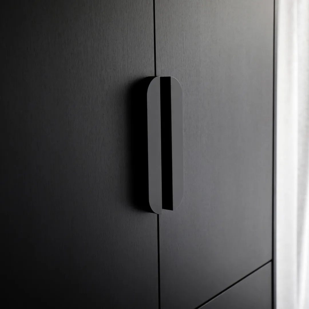 Minimalist matte black vertical handles on dark textured cabinet doors.