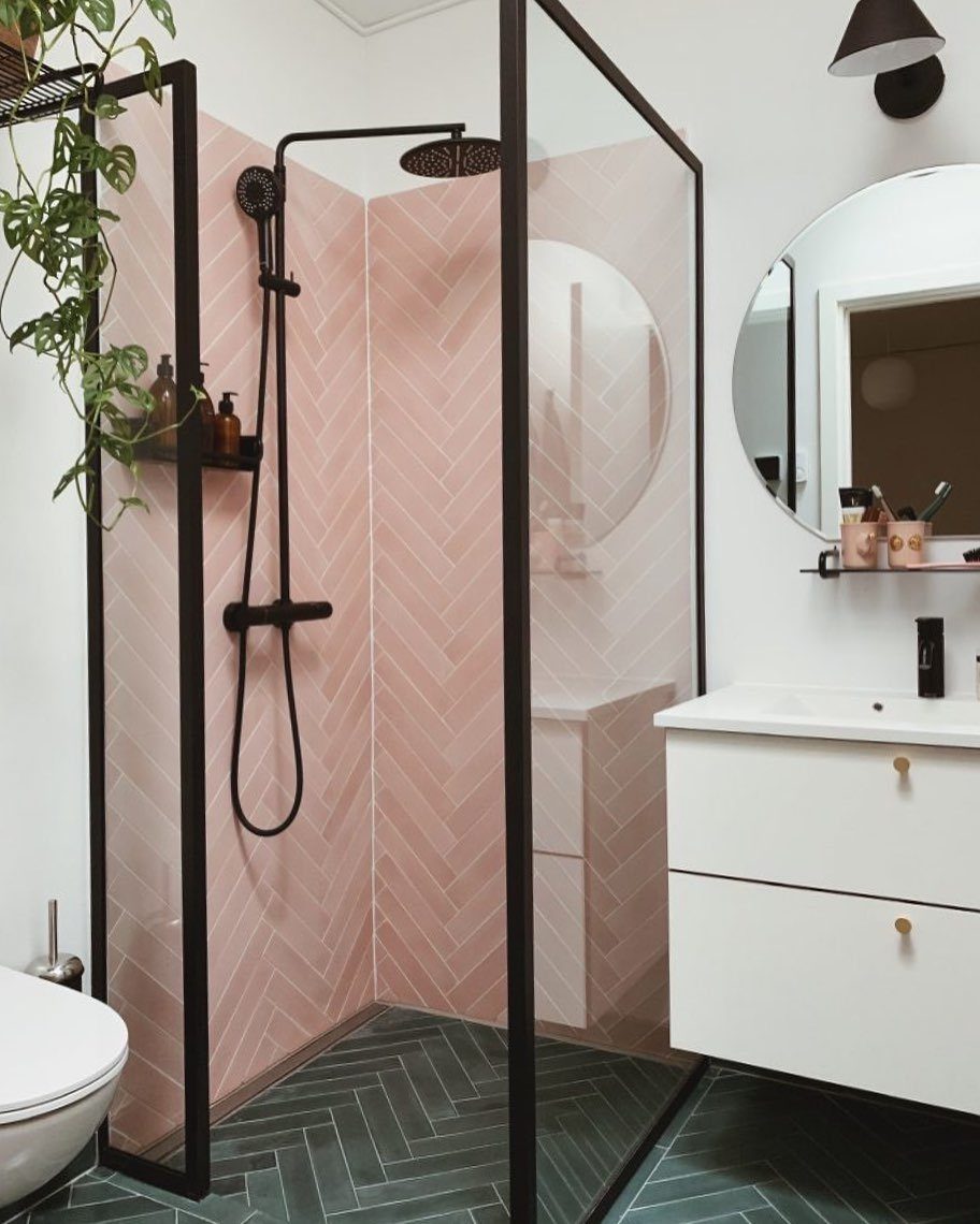 Pink chevron tiles on shower walls and green chevron tiles on the bathroom floor.