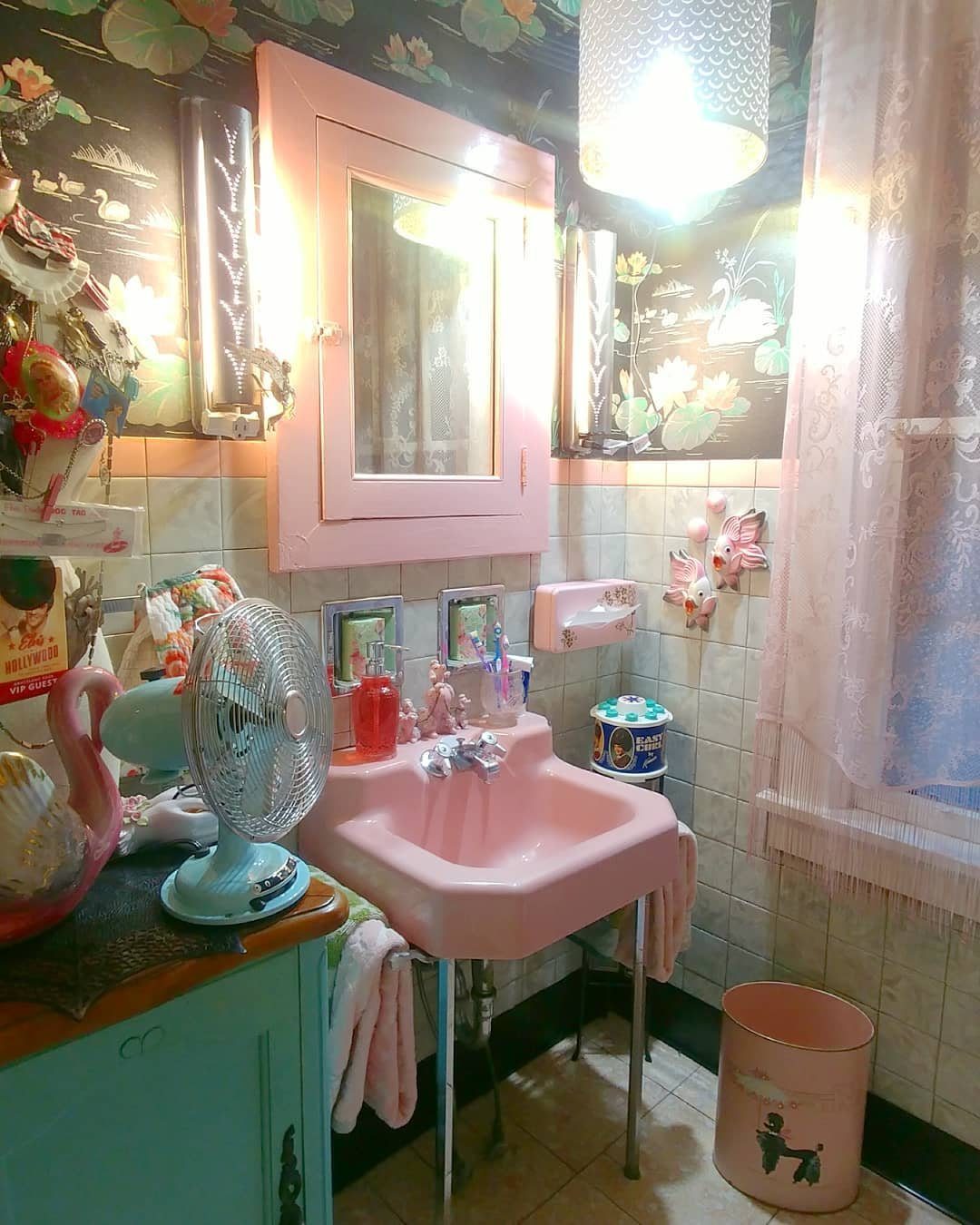 Mint green tiles and pink sink in a decorated vintage-style bathroom.
