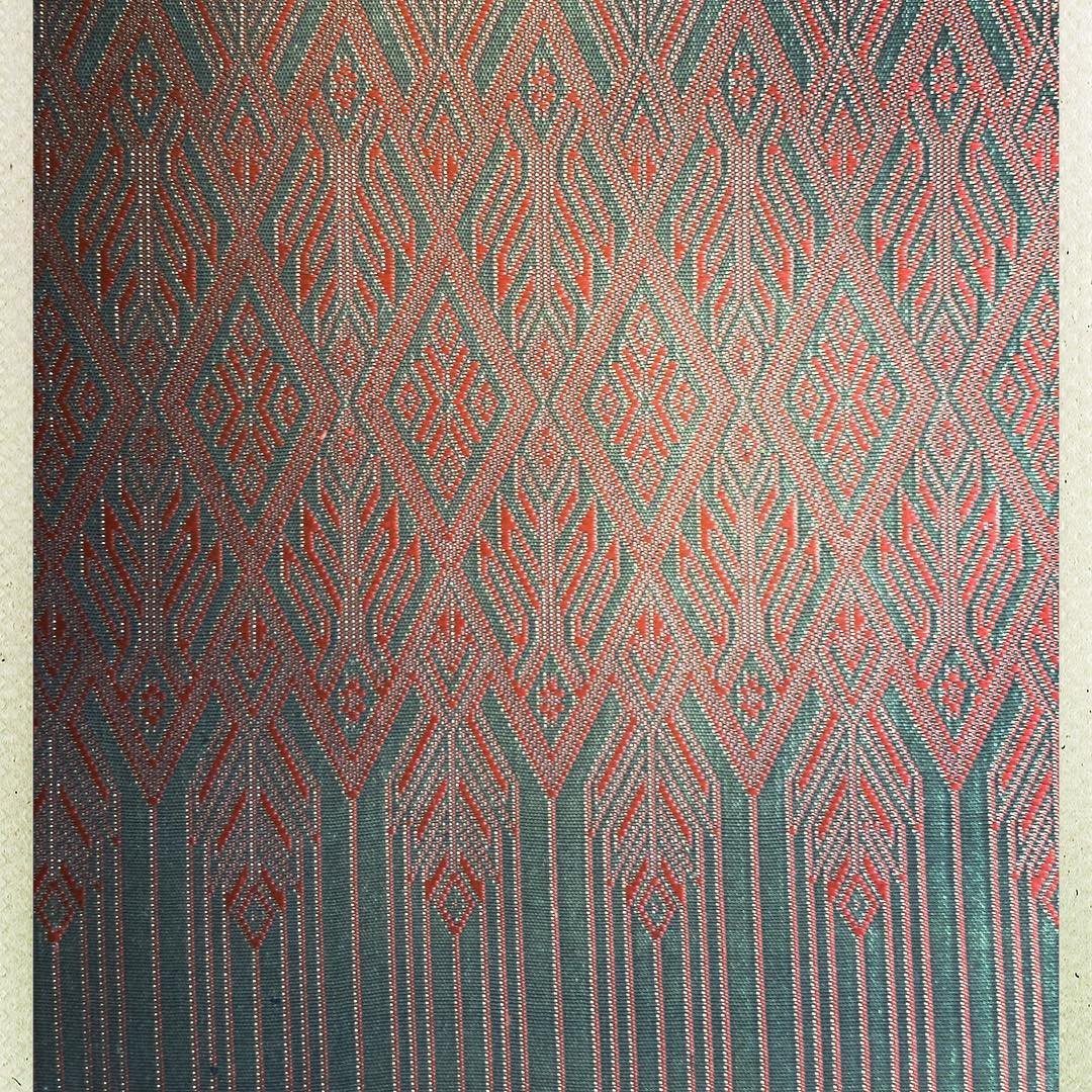 Pink and green patterned woven fabric with a repeating diamond and flame motif.