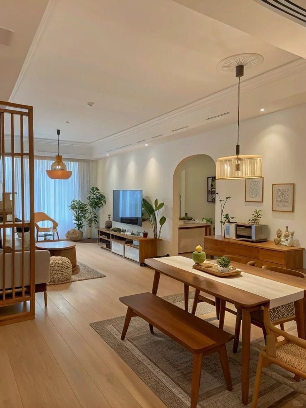 A modern dining room with a wooden table, bench, and warm pendant lighting.