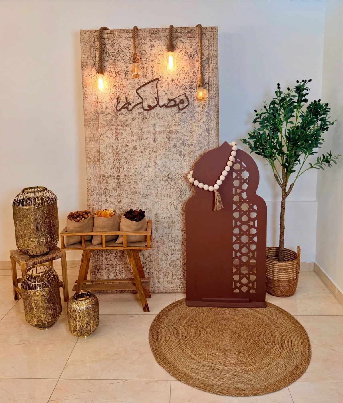 Ramadan decor corner with hanging lights, gold lanterns, a snack cart, and an arched decorative panel.
