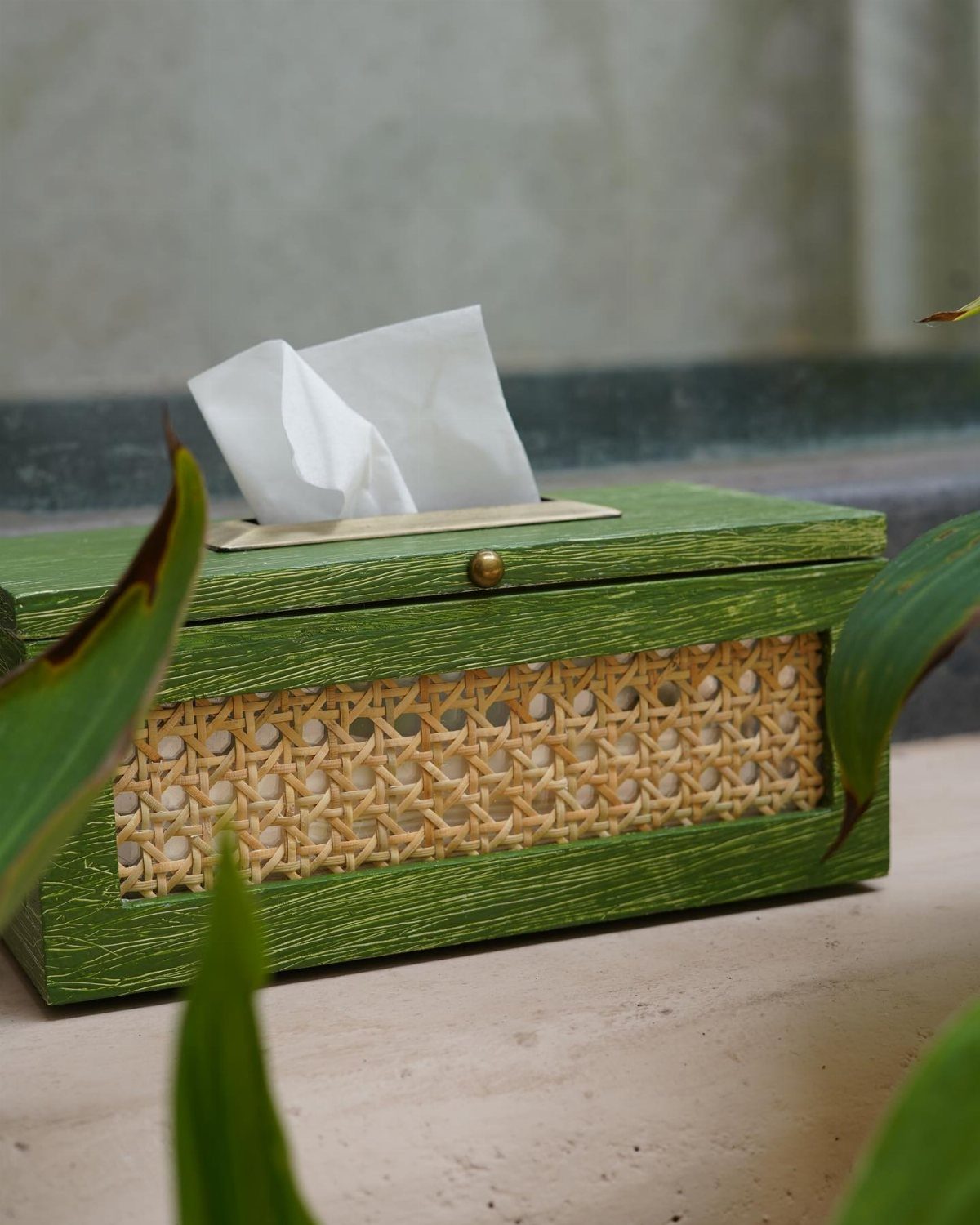 Green wooden tissue box with a woven rattan design and white tissues inside.