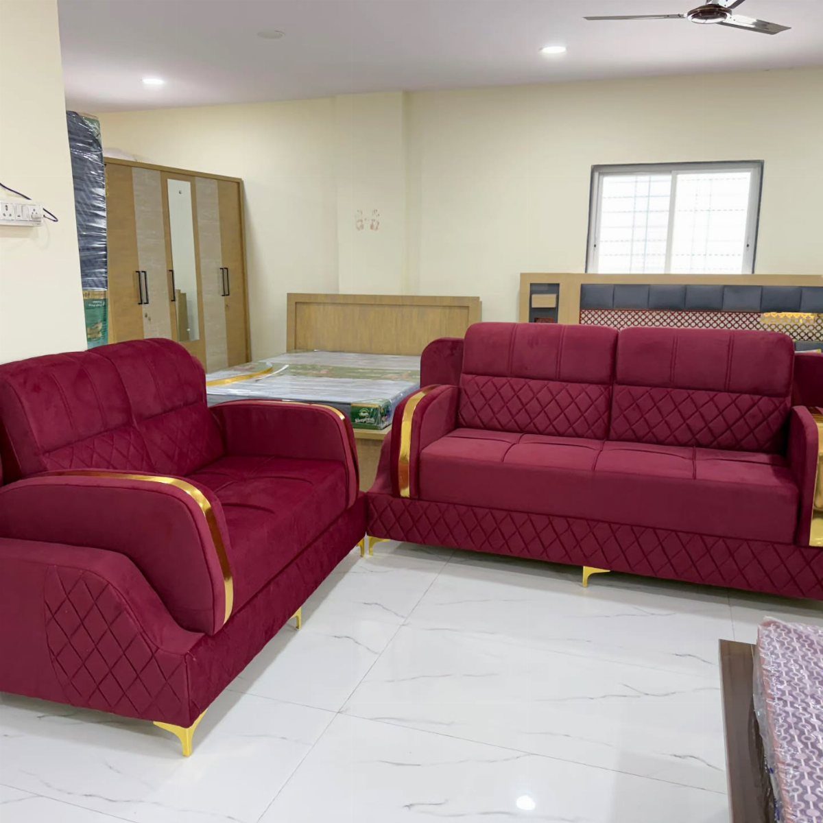Red velvet sofas with gold accents and diamond tufting on a white marble floor.