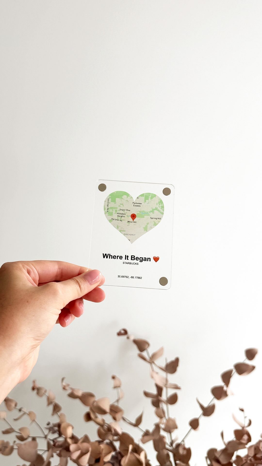 A hand holding a small rectangular card with a heart-shaped map design.
