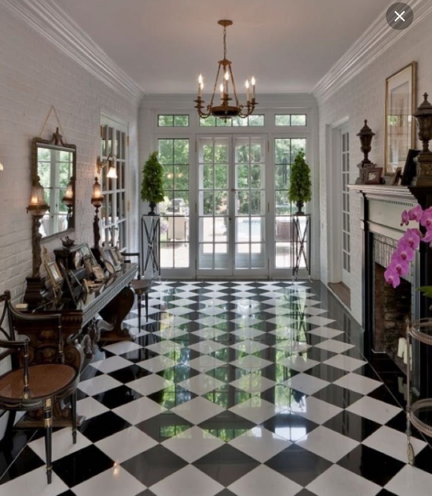Black and white checkered flooring in a bright, elegant hallway with large glass doors.
