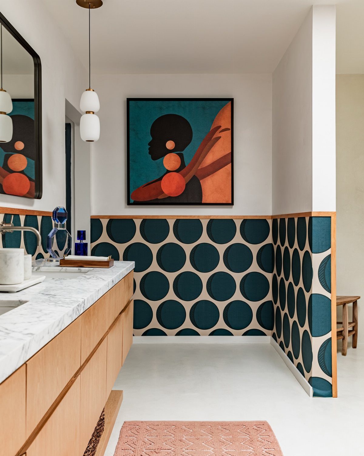 Modern bathroom with marble counters, wooden cabinets, and teal circular patterned tiles.