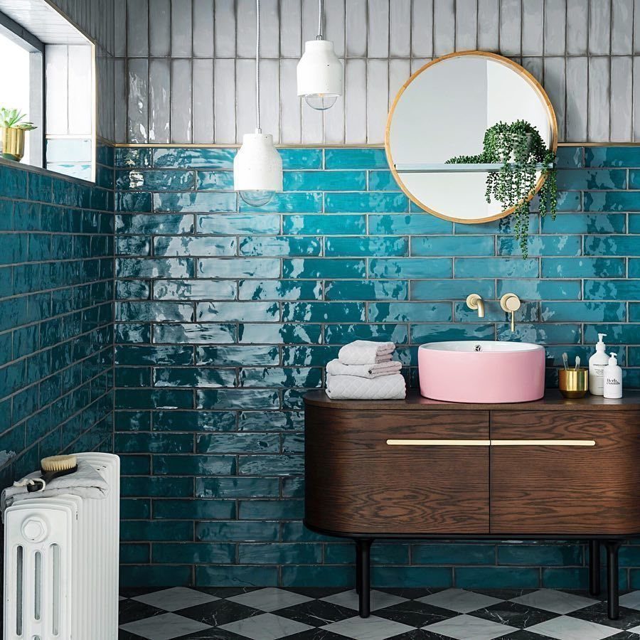 Teal subway tiles on a bathroom wall with a wooden vanity and pink sink.