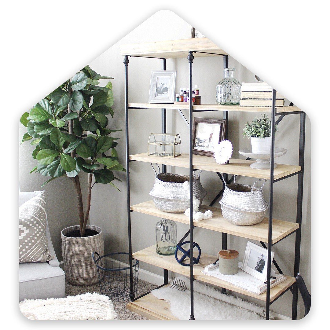 Wooden shelving unit displaying framed photos, woven baskets, books, and small decorative items in a room.