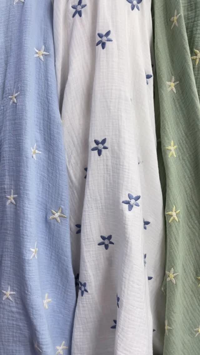 Draped light blue, white, and sage green fabrics with small embroidered star patterns.