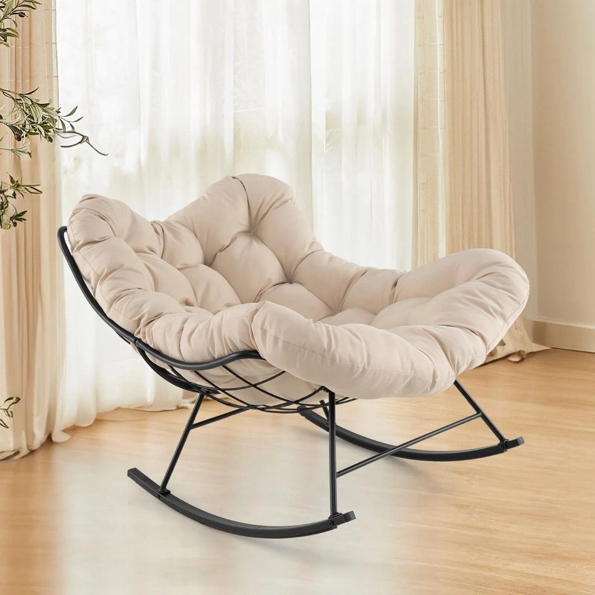 A black metal rocking chair with a tufted beige cushion sits on a light wood floor.