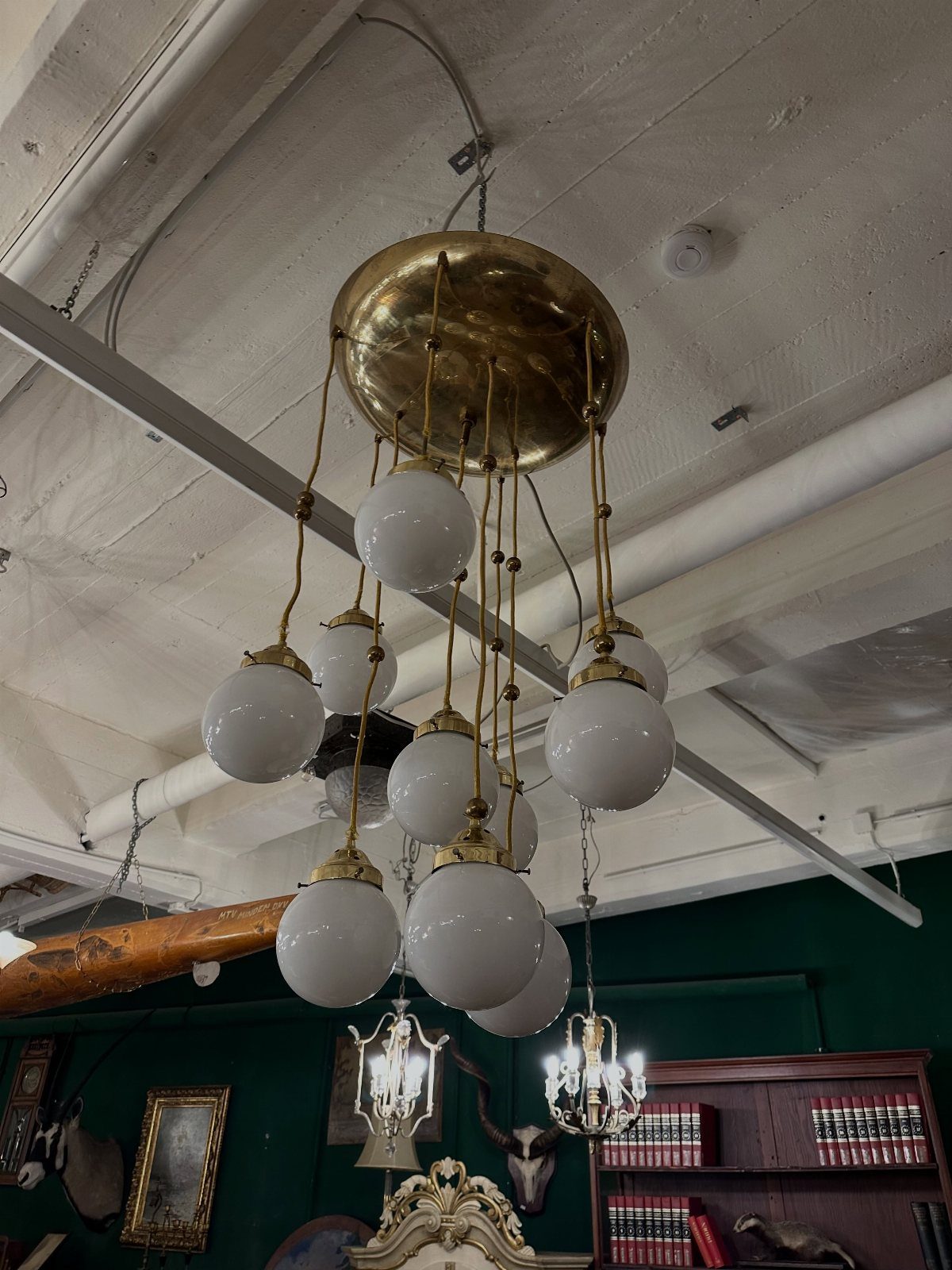 Vintage brass chandelier with multiple frosted white globe lights hanging from a white ceiling.