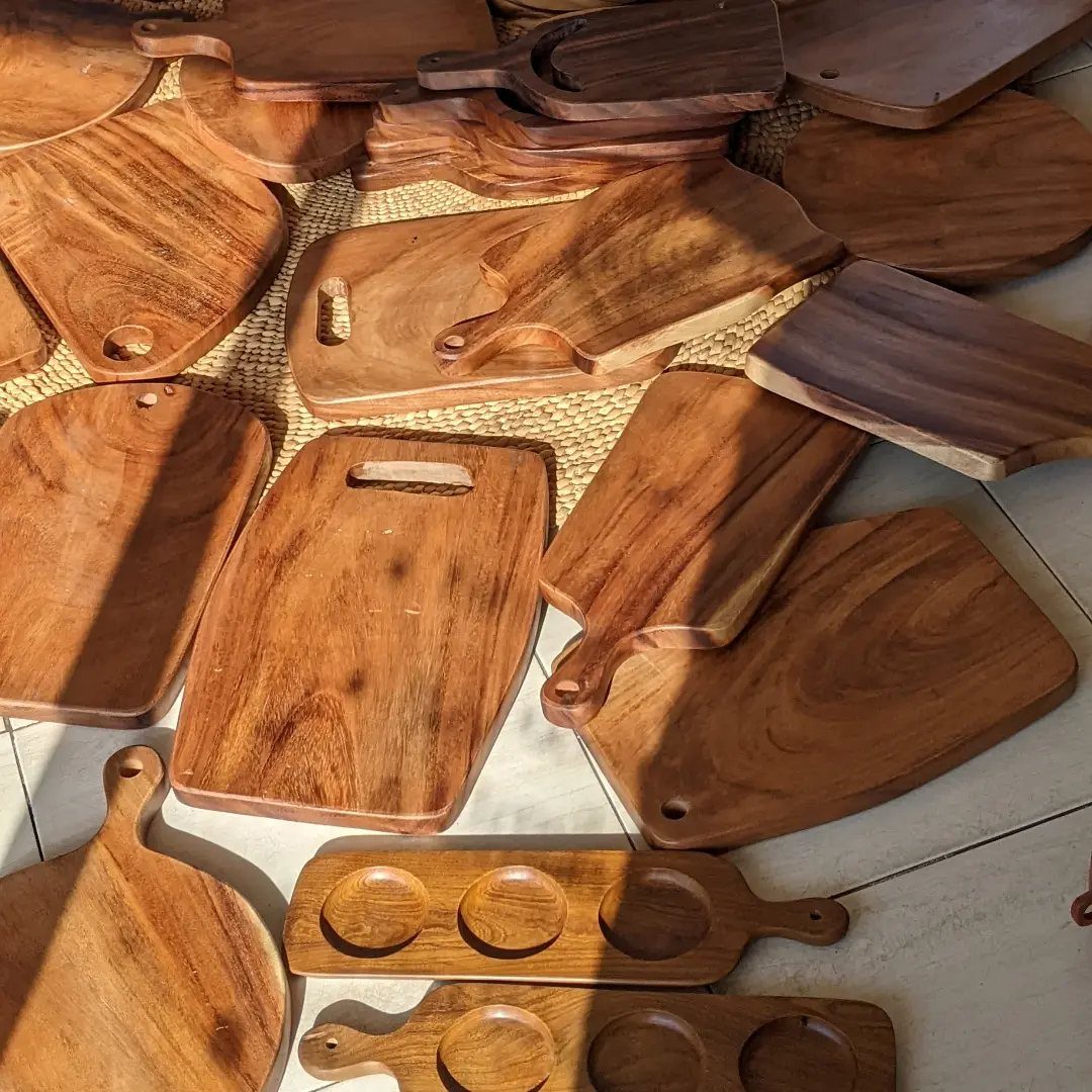 Multiple wooden cutting boards of various shapes and sizes scattered on a surface.
