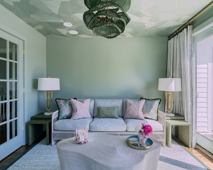 Sage green walls and a geometric patterned green ceiling in a modern living room with a gray sofa.