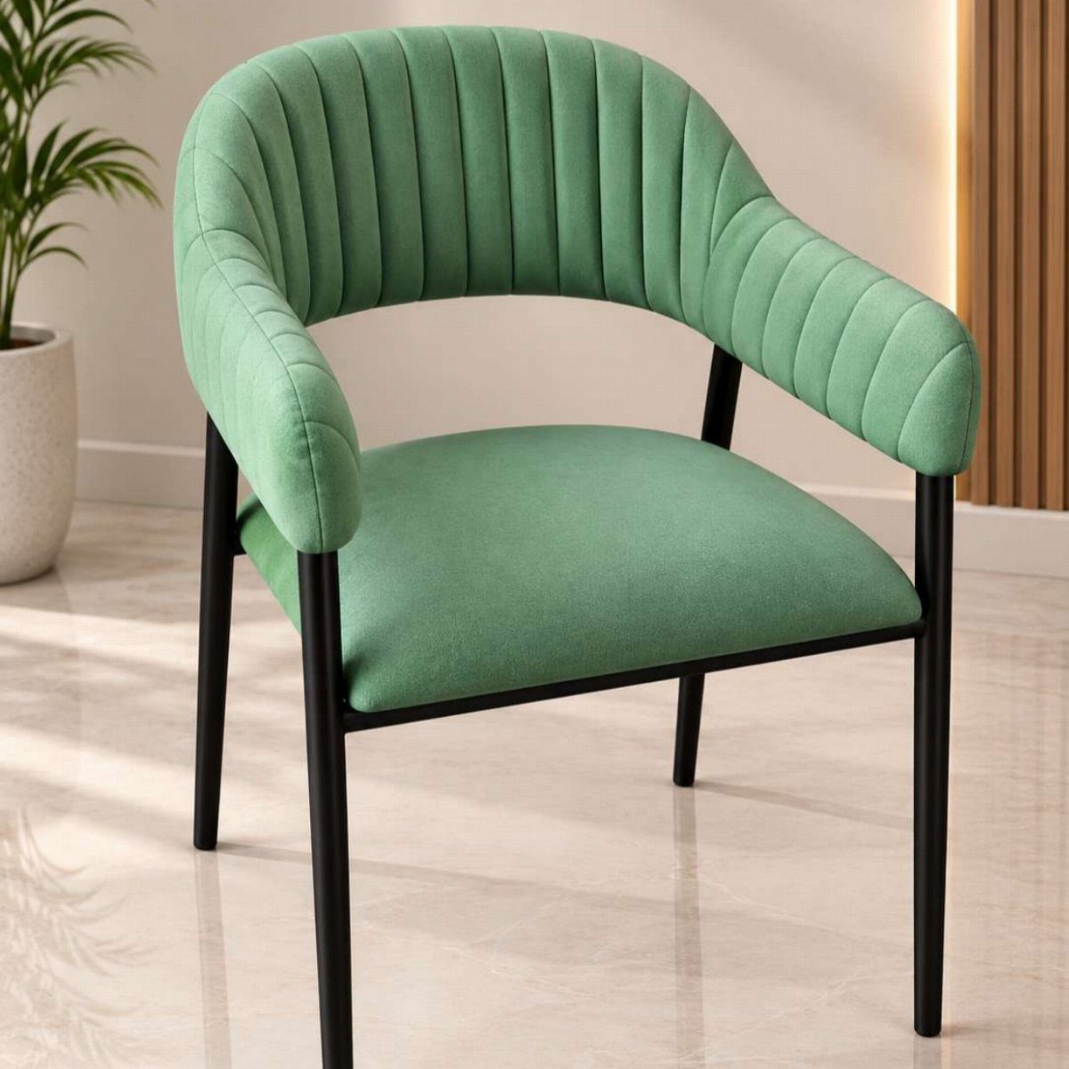 A sage green ribbed velvet accent chair with thin black metal legs on a light floor.