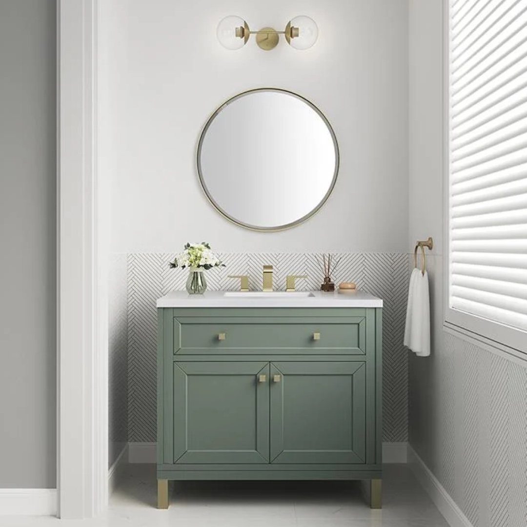 Sage green vanity with gold faucets, gold hardware, and a round gold-rimmed mirror.