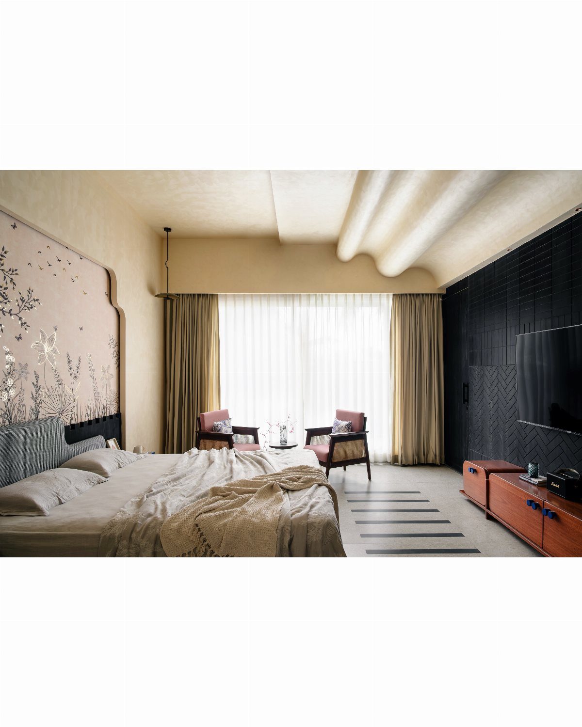 A modern bedroom with a large bed, armchairs, and a textured wavy ceiling design.