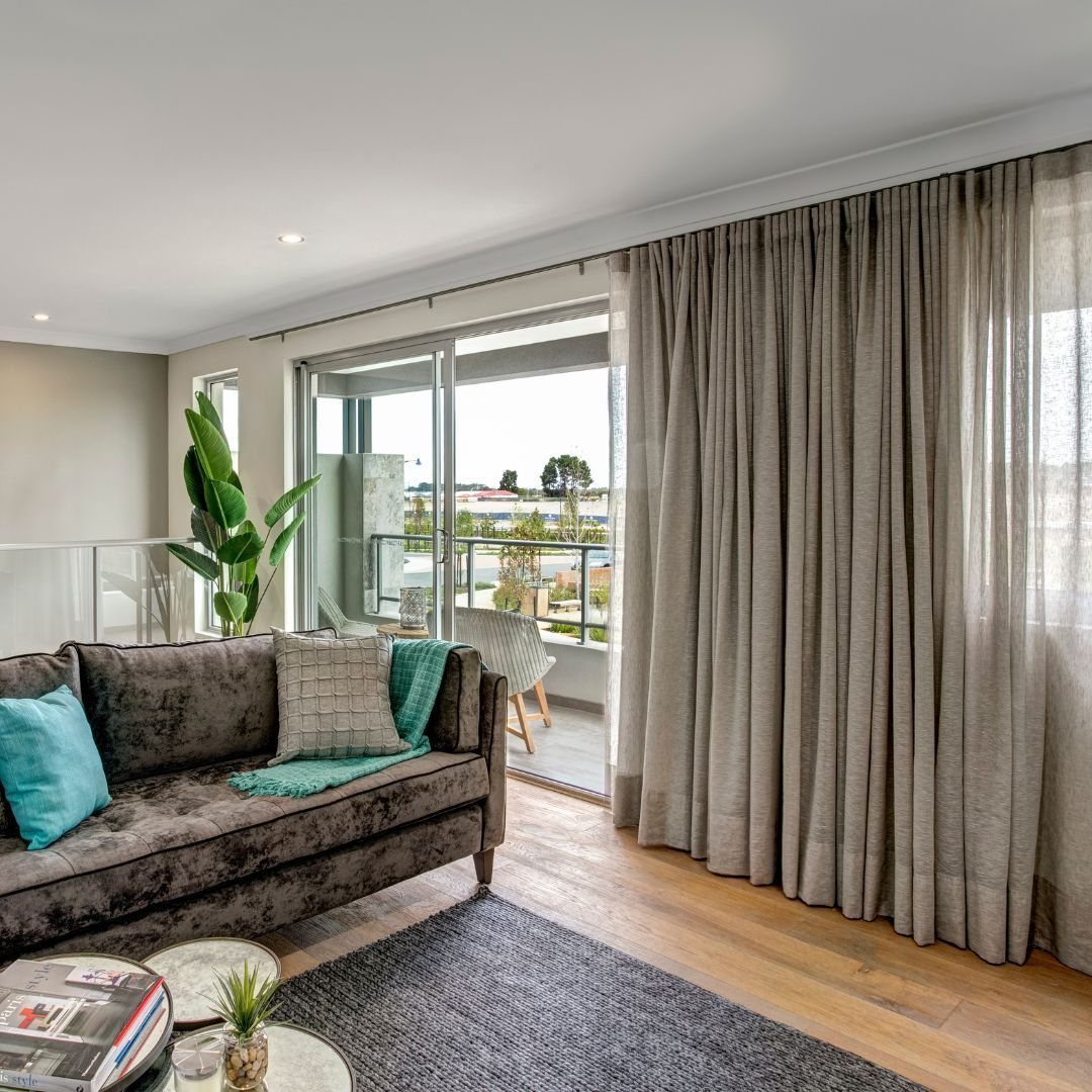 Neutral floor-to-ceiling curtains hanging beside a sliding glass door in a modern living room.
