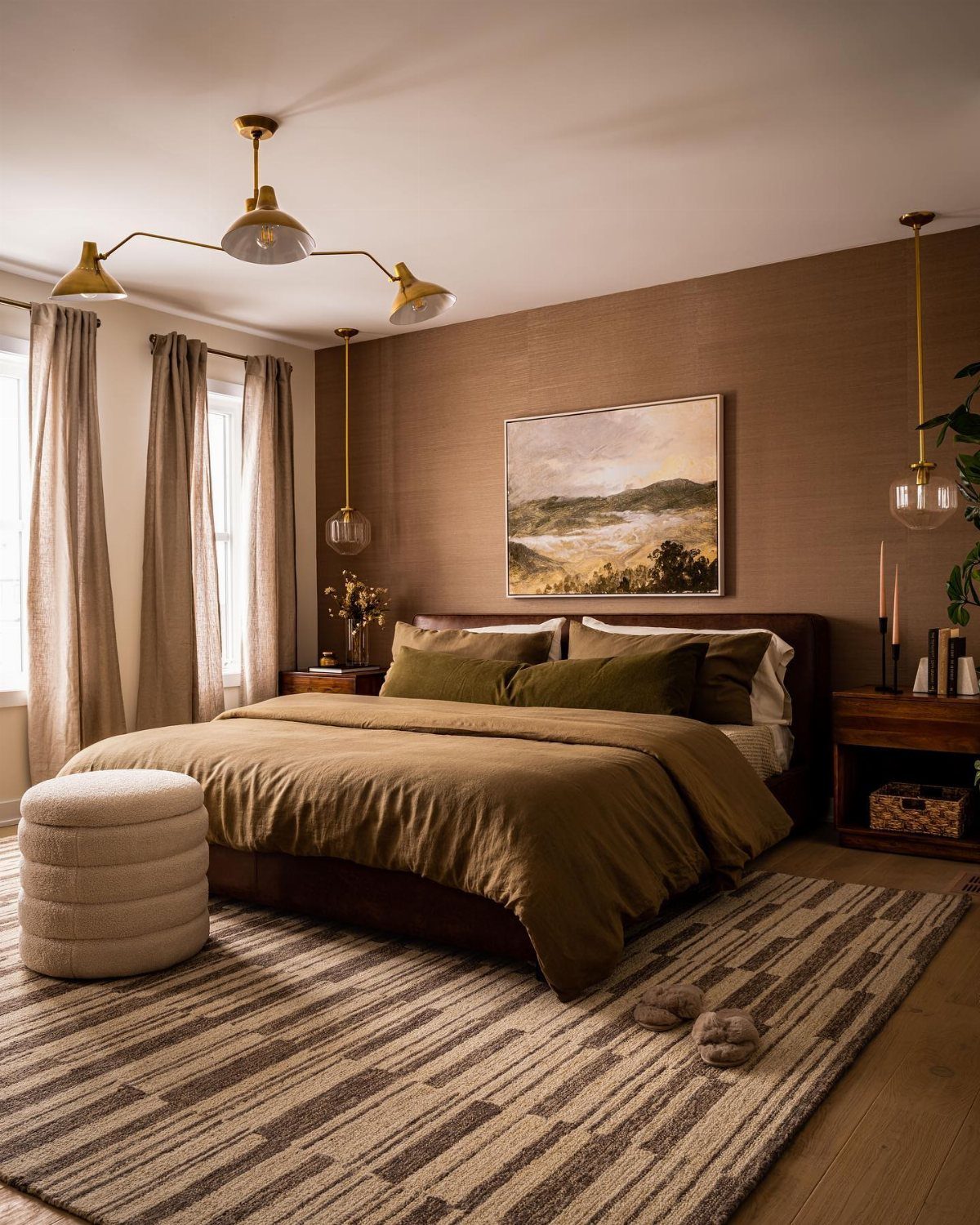 A cozy bedroom with olive green bedding, textured brown walls, and gold sculptural lighting fixtures.