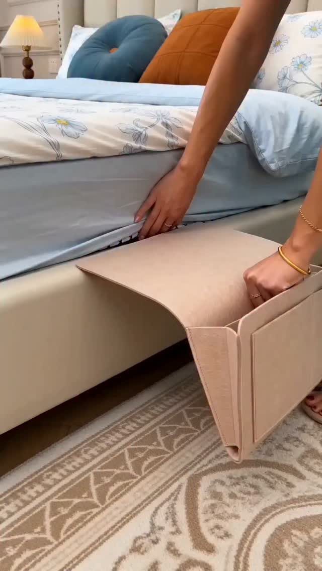 Hands sliding a beige fabric storage bin under a light blue bed frame.