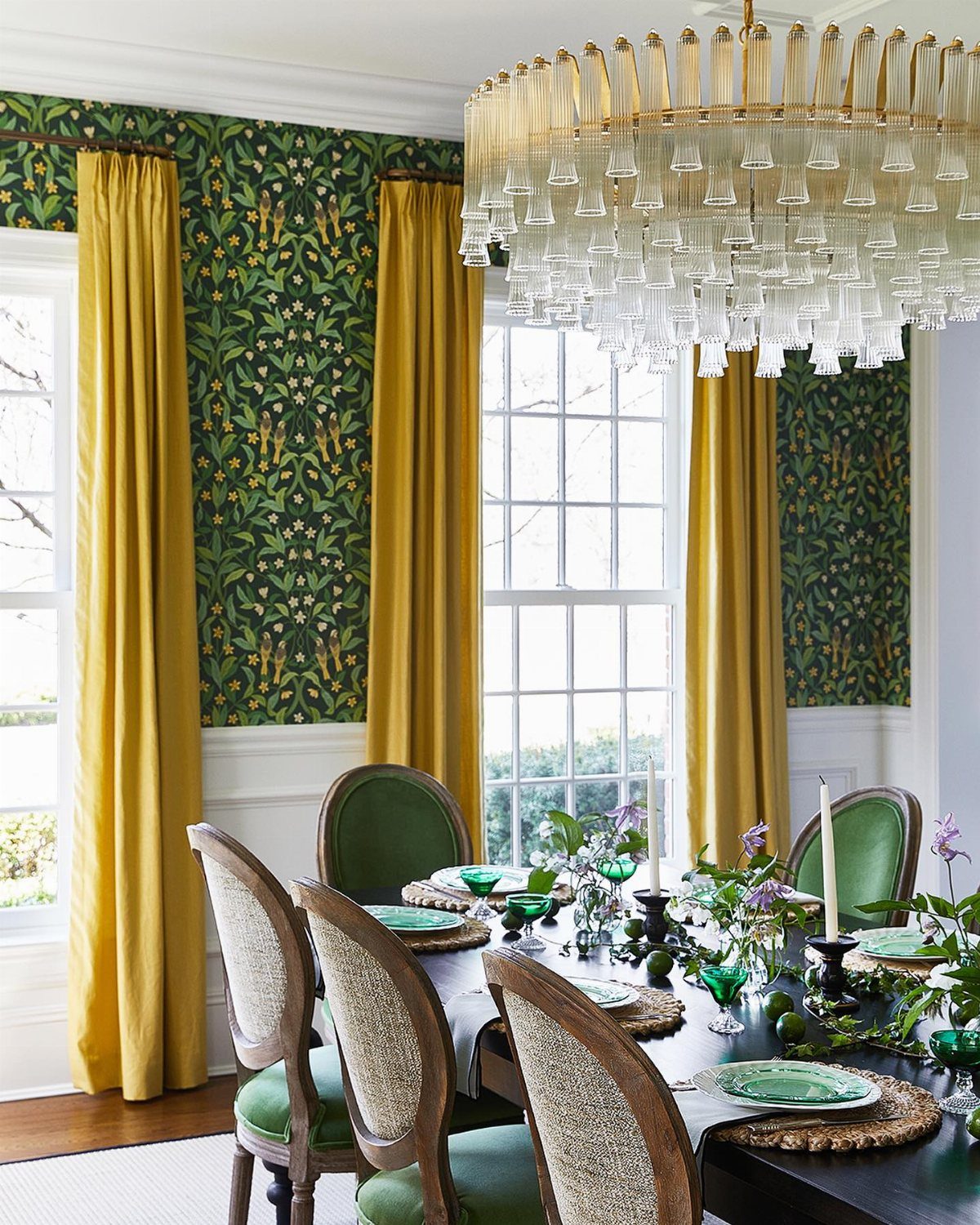 Large tiered glass chandelier hanging over a set dining table in a green and yellow room.