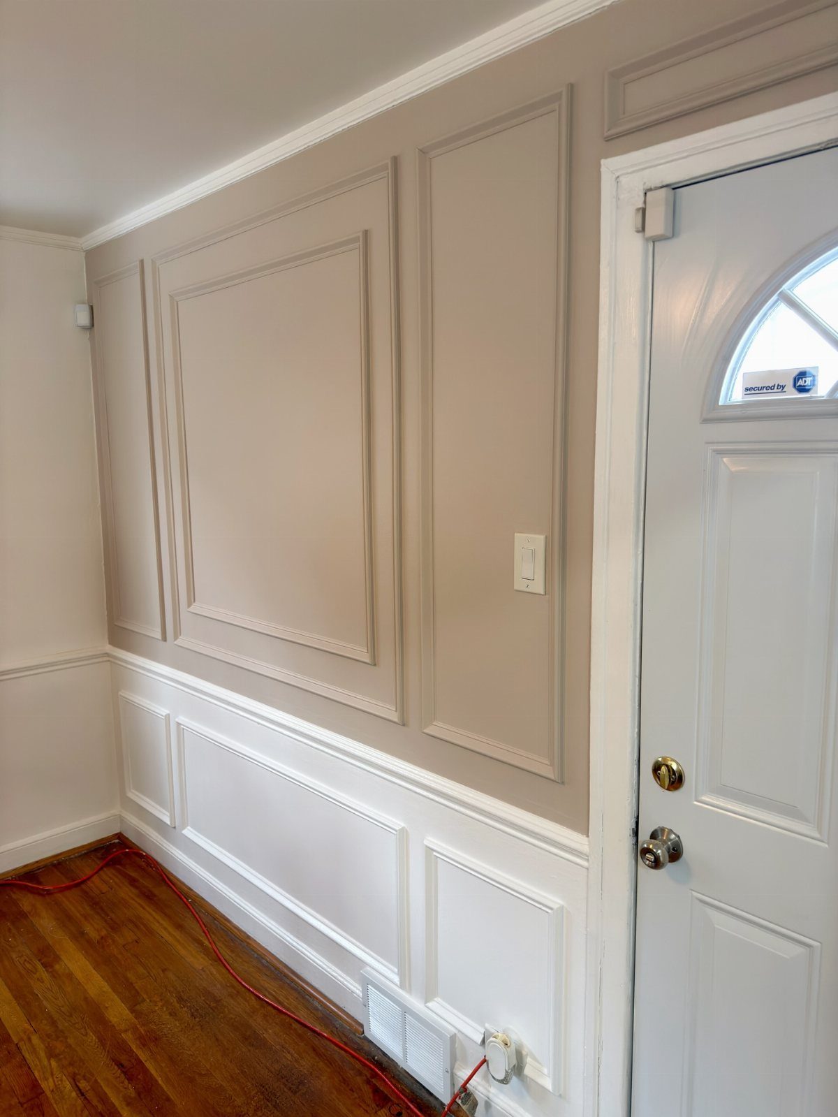 Wainscoting and decorative wall molding painted in two different colors on a dining room wall.