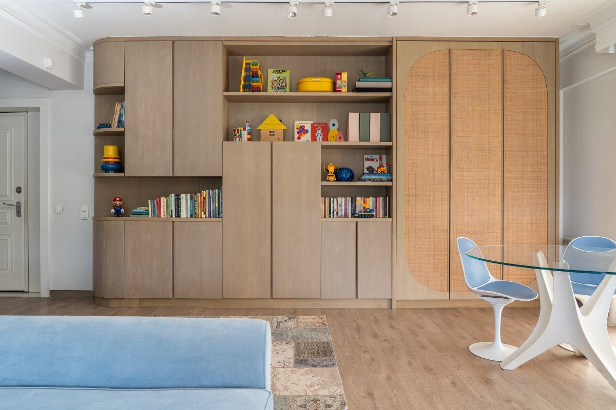 Large light wood built-in storage unit with books and toys against a white wall.