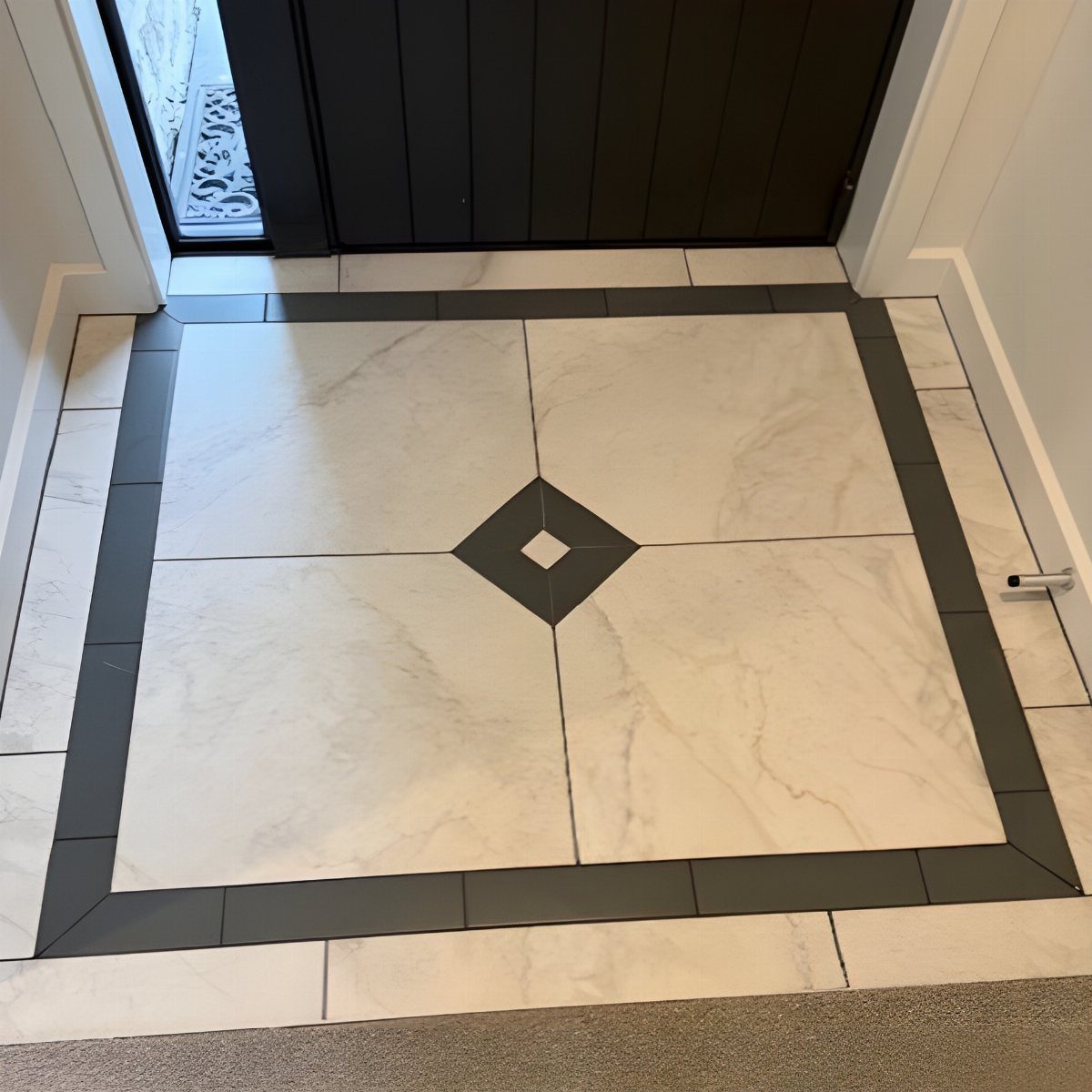 White marble tiles with a dark grey border and diamond accent in an entryway.